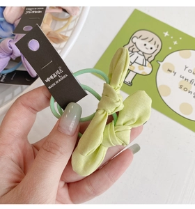 Vue détaillée d'un chouchou noeud en tissu vert clair sur son support de présentation