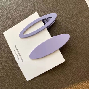 Detail view of purple matte oval hair clips with solid and hollow designs on card