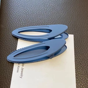 Close-up of two matte blue oval cutout hair clips on a card for daily styling