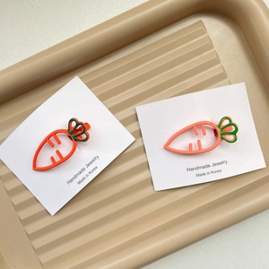 Détail de pinces à cheveux carotte mignonnes avec design creux en métal orange sur carte