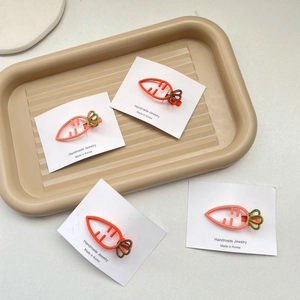 Vue détaillée de quatre barrettes à cheveux carotte orange avec feuilles vertes