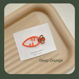 Gros plan sur une pince à cheveux carotte orange foncé avec carte de présentation bijoux