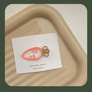 Gros plan d'une barrette à cheveux en forme de carotte orange clair sur carte cadeau