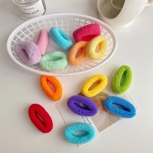 Détail d'élastiques à cheveux colorés en tissu éponge dans un panier blanc pour filles