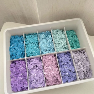 Mini barrettes colorées de 2cm en métal organisées dans une boîte de rangement blanche