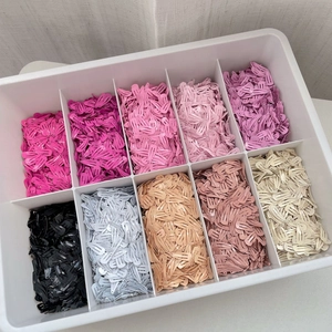 Gros plan de barrettes clic-clac colorées de 2cm dans une boîte de rangement compartimentée