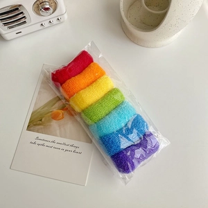 Détail de sept chouchous en peluche aux couleurs de l'arc-en-ciel sous emballage