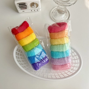 Lot de chouchous arc-en-ciel en peluche aux couleurs vives sur un bureau blanc