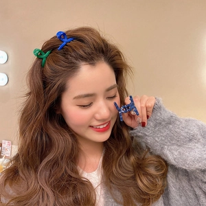 Close-up of vibrant blue and green mini hair claws worn as side clips for styling