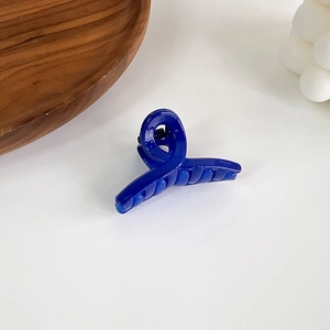 Close-up of a Klein blue hair claw clip with glossy finish and spiral twisted design