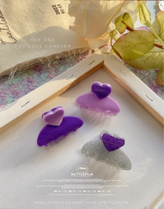 Detailed view of three purple and glitter heart claw clips arranged in a frame