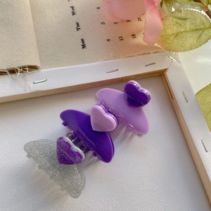 Mini heart hair claws in purple and silver glitter displayed on a vintage frame