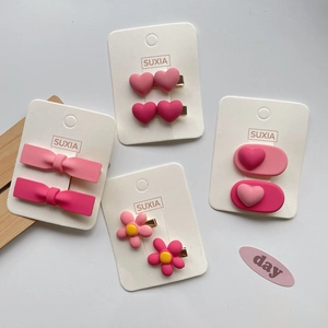 Detailed set of four pink resin hair clips including bows and hearts on display card