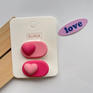 Close-up of pink heart-shaped hair clips in two shades on a white display card