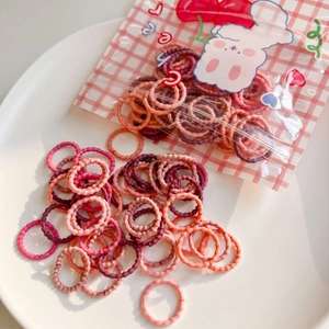 Colorful mini elastic hair ties in a cute cartoon bunny zipper pouch on a ceramic plate