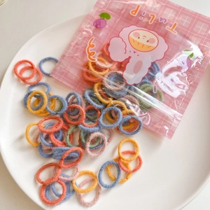 Close-up of soft candy-colored plush hair ties in a cute cartoon sheep packaging bag