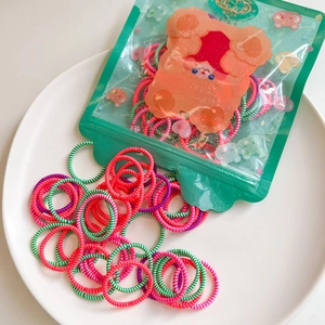 Detailed close-up of colorful striped elastic hair bands in transparent bear packaging