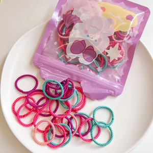 Macro shot of colorful elastic baby hair ties spilling from cartoon pouch into white bowl