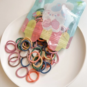 Close-up of colorful mini elastic hair bands in a cute bear zip bag on a ceramic plate