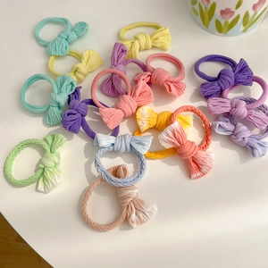 Assortment of macaron-colored fabric bow hair ties scattered on a clean white surface
