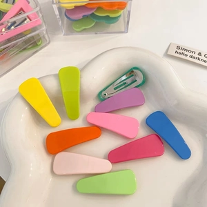 Macro shot of colorful candy-colored metal hair clips in a white cloud ceramic dish