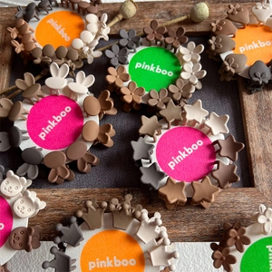 Close-up of mini flower and star hair claws in earthy tones on a round display card
