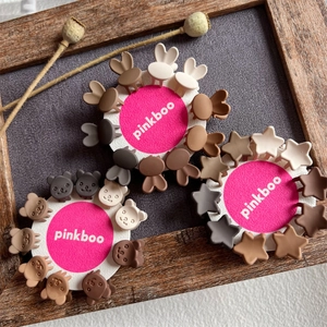 Mini floral and star hair claws in earthy tones displayed on a white card over grey wood