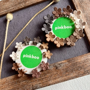 Mini daisy flower hair clips in earthy matte colors on branded display cards