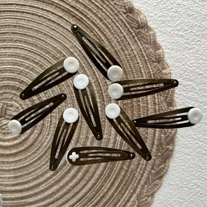 Vintage bronze snap hair clips set with white resin accents on woven straw mat