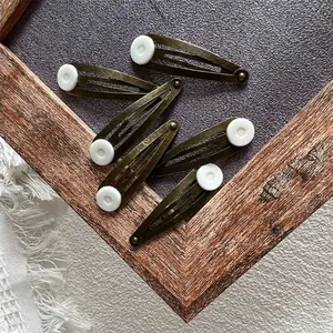 Vintage bronze snap hair clips set with white button accents in a 5-piece collection