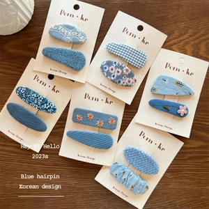 Haarklammern-Set mit blauem Blumenmuster und Karo auf Displaykarte mit Holzgrund