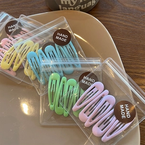 Detail of colorful macaron hair clips in hand made packaging displayed on a ceramic plate