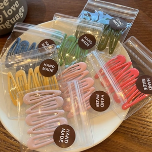 Candy-colored water drop hair clips set in transparent packaging on a white tray