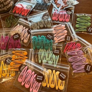 Macro detail of assorted colorful drip glaze metal BB hair clips in clear packaging