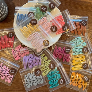Detail view of candy-colored metal hair clips in handmade packaging with matte finish