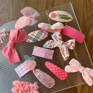 Detailaufnahme von rosa Stoff-Haarspangen mit floralen Schleifen und Pailletten-Ohren