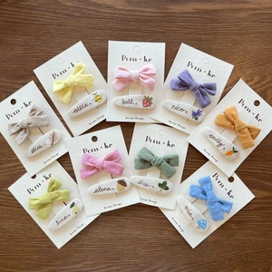 Detail of handmade embroidered bow hair clips in various Morandi colors on wood background