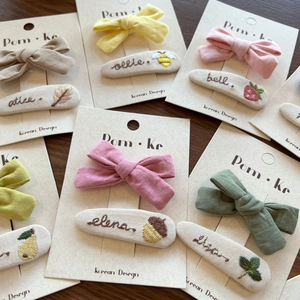 Flat lay of embroidered bow hair clips and hairpins on a dark wood background