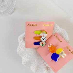 Detail of colorful acrylic rainbow flower hair clips on pink display card with lace background