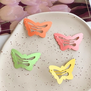 Close-up of four matte colorful butterfly hair clips on a decorative ceramic plate
