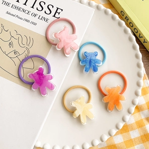 Lot d'élastiques à cheveux ours en acétate coloré sur une assiette en céramique blanche