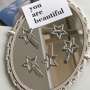 Close-up of five minimalist silver star hair clips on a vintage mirror surface