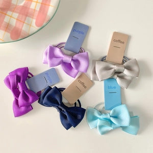 Detailed macro view of colorful bow hair ties on ribbed ribbon with color labels