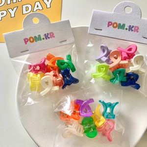 Macro shot of colorful mini hair clips in branded transparent polybag packaging