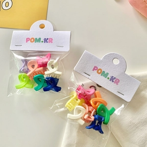 Close-up of colorful mini hair clips in transparent candy color packs on white background