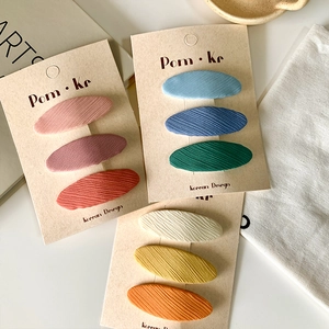 Set of nine colorful fabric oval hair clips in pink blue and yellow on display cards