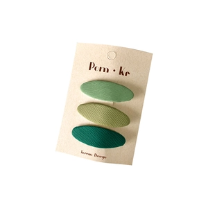 Three-piece set of oval fabric hair clips in gradient green tones on a display card
