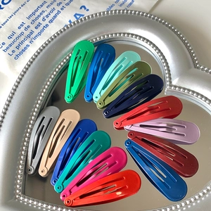 Macro shot of colorful glossy metal snap hair clips in a heart-shaped silver mirror tray
