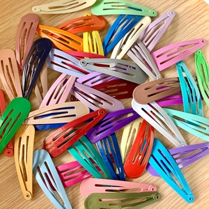 Vibrant 5cm glossy painted metal snap hair clips in assorted colors on wooden background