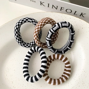 5-piece set of knitted checkerboard hair ties in neutral tones on a ceramic plate